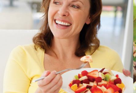 Photo: Happy woman eating a bowl of berries