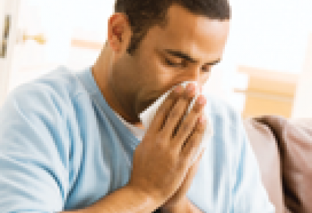 man sneezing with tissue