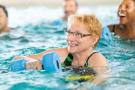 Photo: Smiling mature woman in swimming pool, taking a water exercise class.